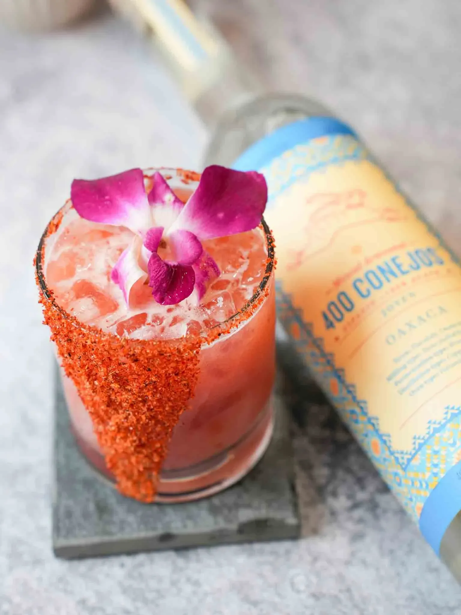 A mezcal cocktail beside a bottle of 400 Conejos