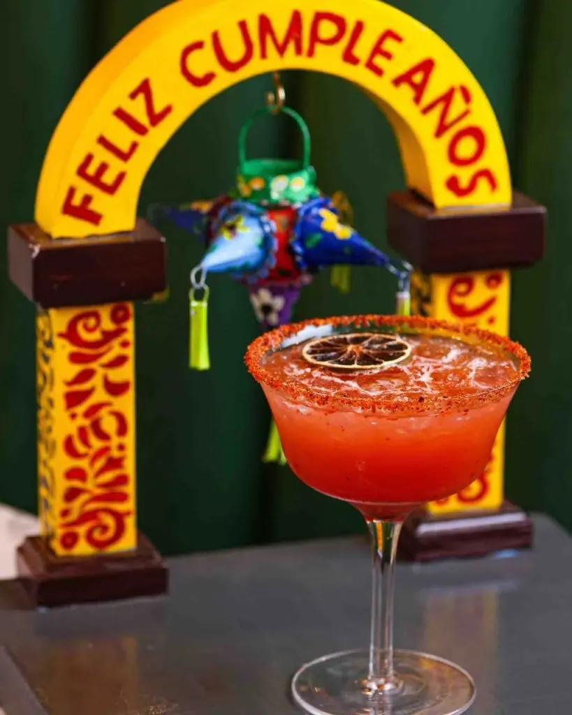 A birthday margarita under a Feliz Cumpleaños arch